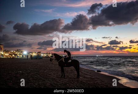 Gaza, Palästina. 24. Dezember 2022. Ein Palästinenser reitet sein Pferd am Ufer des Mittelmeers in Gaza City. Kredit: SOPA Images Limited/Alamy Live News Stockfoto