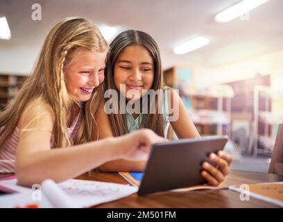 Verbesserung des Lernerlebnisses. Zwei junge Mädchen, die in der Schule ein digitales Tablet benutzen. Stockfoto