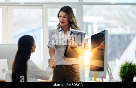Danke, dass Sie sich Zeit genommen haben. Zwei junge Geschäftsfrauen begrüßen sich im Büro mit einem Händedruck. Stockfoto
