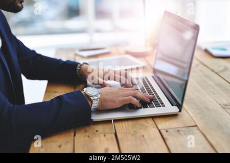 Aus nächster Nähe und mit hoher Produktivität. Ein Geschäftsmann, der einen Laptop an seinem Schreibtisch benutzt. Stockfoto