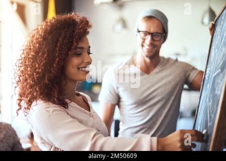 Sie ist ein großer Teil des Erfolgs des Unternehmens. Zwei Geschäftsleute diskutieren ihre Ideen an einer Tafel. Stockfoto