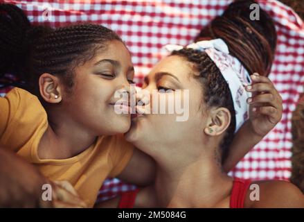 Küsse für meine süßeste. Ein Foto von einer Mutter, die ihrer kleinen Tochter einen Kuss auf die Wange gibt. Stockfoto