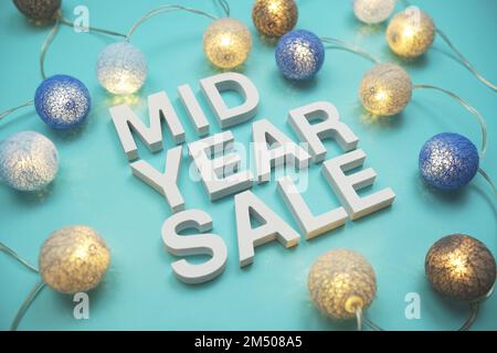 Die Buchstaben des Alphabets „Mid Year Sale“ sind mit LED-Baumwollkugeln auf blauem Hintergrund dekoriert Stockfoto