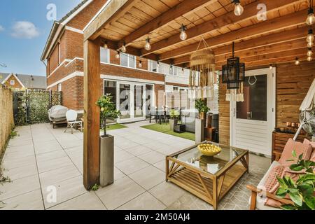 Ein Wohnbereich im Freien mit Terrassenmöbeln und Topfpflanzen an der Seite des Hauses, umgeben von Backsteinwänden Stockfoto