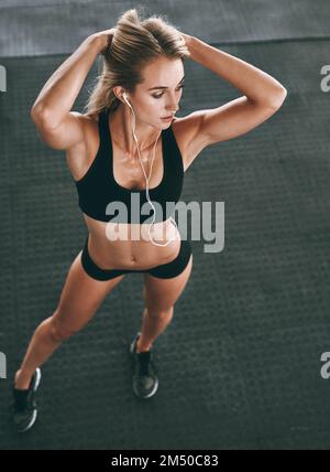 Die Belohnung ist es wert. Eine gut gebaute Frau, die im Fitnessstudio posiert. Stockfoto