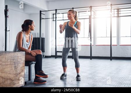 Bereit machen zum Angriff. Eine Fitnesstrainerin, die mit ihrem Klienten in einem Fitnessstudio spricht. Stockfoto