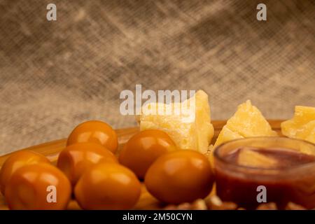 Verschiedene Sorten von Käse, Walnusskernen und geräucherten Wachteleiern auf einer Holzoberfläche. Stockfoto