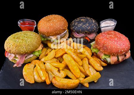 Gemischte Burger mit Fleisch und Fisch, Bratkartoffeln und Saucen auf schwarzem Hintergrund Stockfoto