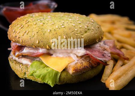 Burger mit Roastfleisch, Speck, Käse und Sauce, mit Kartoffeln und Sauce auf verschwommenem Hintergrund Stockfoto