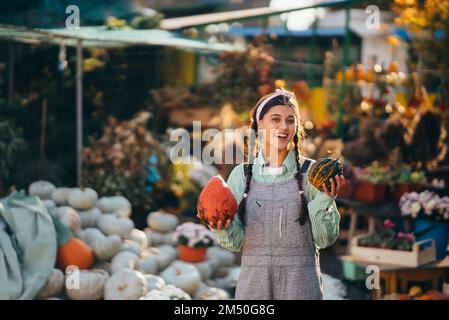 Eine junge Verkäuferin zeigt die Herbsternte Stockfoto