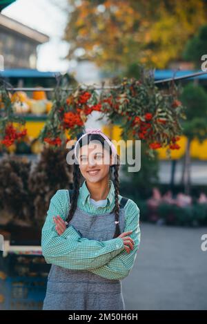 Verspielte Bäuerin im Denim-Overall lächelt aufrichtig, während sie posiert. Stockfoto