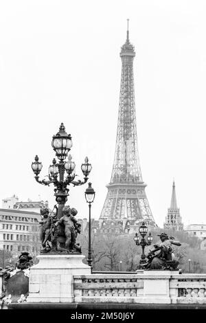 Eine vertikale Graustufenansicht des Eiffelturms von der Brücke Pont Alexandre III in Paris, Frankreich Stockfoto