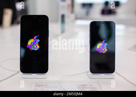 Apple iPhone 12 und Apple iPhone SE mit Apple Logo auf dem Bildschirm werden im Apple Store verkauft. Minsk, Weißrussland - Februar 2022 Stockfoto