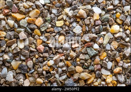 Feuchte Straße und Gipsabrieb, lose Absplitterungen, zerkleinerter Stein, Oberfläche, von oben. Kalk- und eisenfreier Quarzsand, der als Streugut verwendet wird. Stockfoto