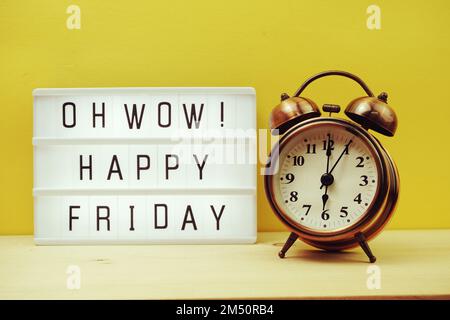 Happy Friday Text in Lightbox mit Wecker auf gelbem Hintergrund Stockfoto