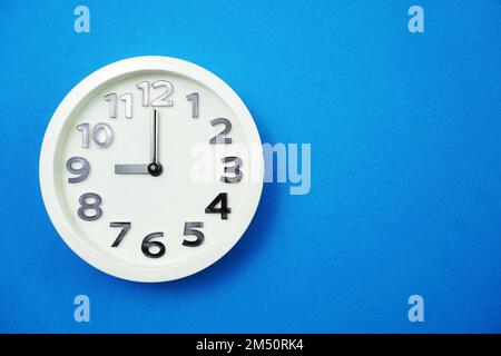 Weiße Uhr mit 9 Uhr auf blauem Hintergrund Stockfoto