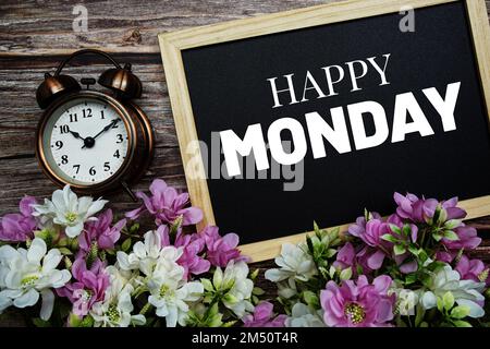 Happy Monday Typografie Text geschrieben auf Holztafel mit Blumenstrauß dekoriert auf Holzhintergrund Stockfoto
