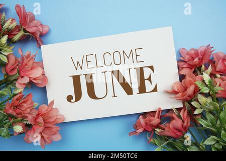 Begrüßungsnachricht im Juni mit Blumendekoration auf blauem Hintergrund Stockfoto