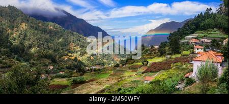 Naturlandschaft der Insel Madeira. Atemberaubender Blick auf die Berge mit Regenbogen über einem kleinen Dorf in der Nähe von San Vicente Stockfoto