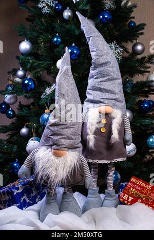 Weihnachtselfen-Dekoration. Vier Zwerge mit Weihnachtsgeschenk sitzen auf einem Holzregal. Weihnachtskonzept und Neujahrskonzept, Grußkarte Stockfoto