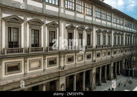 Die Kolonnaden der Uffizien-Kunstgalerie sehen Sie von einem Gang des Museums aus mit Touristen und Statuen bemerkenswerter Menschen. Stockfoto