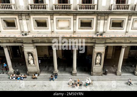 Die Kolonnaden der Uffizien-Kunstgalerie sehen Sie von einem Gang des Museums aus mit Touristen und Statuen bemerkenswerter Menschen. Stockfoto