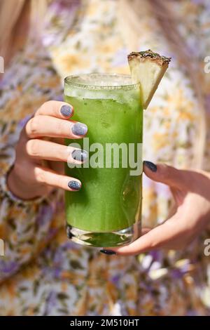 Kalter Sommercocktail in der Hand der Frau, Nahaufnahme. Die Hand einer Frau hält in einem Sommerkaffee ein beschlagenes Glas eines erfrischenden Cocktails mit Zitrone und Eis. Stockfoto