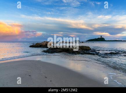 Landschaftsblick auf einen farbenfrohen Sonnenuntergang am Nora Beach in Sardinien mit dem Coltellazzo Tower im Hintergrund Stockfoto