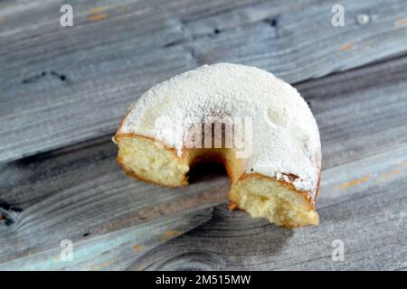 Puderzucker-Ring-Donut, Glasierter, hefegezogener, amerikanischer Ring-Donut mit Garnierung aus fein gemahlenem Zucker der Konditoren, Art der Nahrung Stockfoto