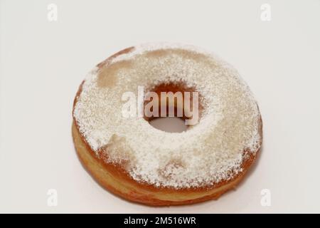 Puderzucker-Ring-Donut, Glasierter, hefegezogener, amerikanischer Ring-Donut mit Garnierung aus fein gemahlenem Zucker der Konditoren, Art der Nahrung Stockfoto