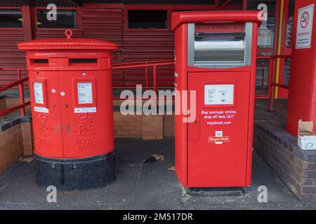 Southend on Sea, Großbritannien. Dezember 2022. Das Royal Mail Delivery Office und das Postzentrum sind in Southend aufgrund von Arbeitskampfmaßnahmen der Communication Workers Union geschlossen. Wo Royal Mail Postfächer vor einem rothäfelten Gebäude in Großbritannien. Die linke Box hat ein traditionelles zylindrisches Design mit zwei Postfächern und Royal Mail-Insignien. Die rechte Box ist eine moderne rechteckige Einheit mit einem digitalen Bildschirm und Beschilderung, die 24/7 Online-Postdienste fördert. Die Gegenüberstellung verdeutlicht die Entwicklung der britischen Postversammlungssysteme. Penelope Barritt/Alamy Live News Stockfoto