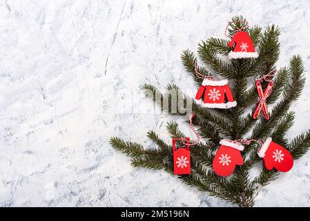 Weihnachts- und Winterzusammensetzung von Tannenzweigen und weihnachtlichen Holzdekorationen auf weißgrauem Hintergrund mit Kopierbereich für Text. Winter und Christus Stockfoto