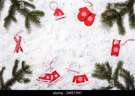 Weihnachts- und Winterzusammensetzung von Tannenzweigen und weihnachtlichen Holzdekorationen auf weißgrauem Hintergrund mit Kopierbereich für Text. Winter und Christus Stockfoto