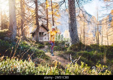 Lächelnde, fröhliche Wanderin, die durch den Herbstwald läuft Stockfoto