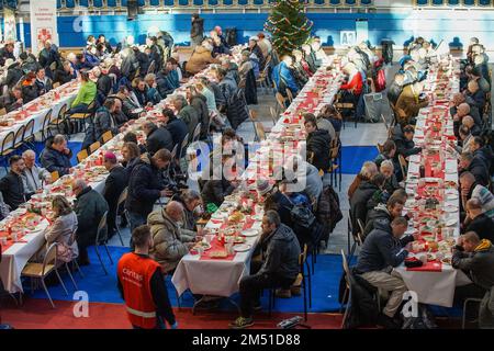 Sopot, Polen. 24. Dezember 2022. Am 24. Dezember 2022 nahmen mehr als 300 Personen an der Weihnachtsfeier in Sopot (Polen) Teil. Die christliche Wohltätigkeitsorganisation Caritas Polens organisierte ein traditionelles polnisches Weihnachtsessen. Die Leute teilten sich eine besondere Waffel, wenn sie Weihnachtsgrüße austauschten. Obdachlose und Arme wurden mit traditionellen polnischen Bigos, Pierogi, Fisch, Brot und Kuchen begrüßt. Kredit: Vadim Pacajev/Alamy Live News Stockfoto