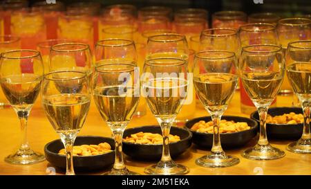 Eine Reihe Gläser mit Wein und Tabletts mit Snacks auf einem Brett. Stockfoto