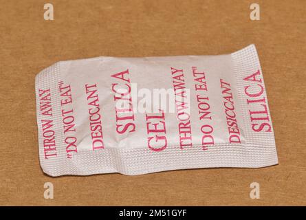 Einzelne Packung Kieselgel, isoliert in einer Faltschachtel, flach liegend. Poröse Trockenmittelsubstanz, die im Verpackungsmaterial zur Aufnahme von Feuchtigkeit verwendet wird. Stockfoto
