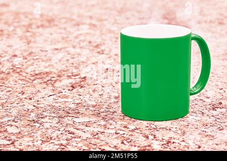 Dunkelgrüner Keramikbecher auf farbenfrohem rotem Hintergrund Stockfoto