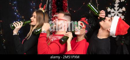 Vier Freunde lehnen sich hintereinander zurück und trinken Bier. Neujahrsfeier Stockfoto
