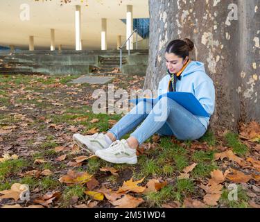 Ein Student sitzt unter einem Baum in der Nähe der Universität und bereitet sich auf Kurse in Österreich, Salzburg vor Stockfoto