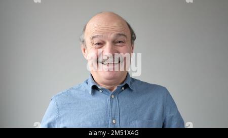 Fröhlicher Senior-Mann, der in die Kamera schaut und lächelt. Stockfoto