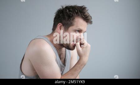 Ein erwachsener Kaukasier, der gestresst und nervös aussieht, mit Fingernägeln beißenden Händen am Mund. Stockfoto
