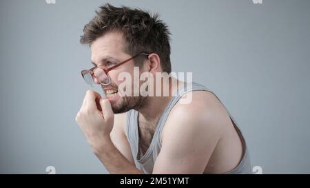 Ein erwachsener Kaukasier, der gestresst und nervös aussieht, mit Fingernägeln beißenden Händen am Mund. Stockfoto