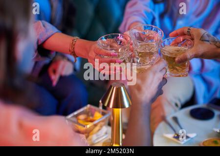 Eine Gruppe junger Leute, die auf einer Party Gläser mit Alkohol klimpern Stockfoto