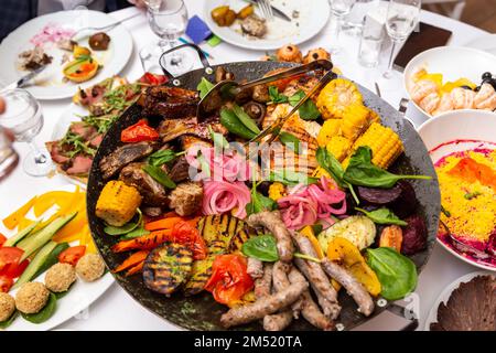 Gemischtes Fleisch und Gemüse, in einem Wok gebraten, auf einer Schüssel mit heißen Kohlen auf dem Tisch, um lange Zeit heiß zu bleiben. Stockfoto