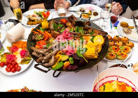 Gemischtes Fleisch und Gemüse, in einem Wok gebraten, auf einer Schüssel mit heißen Kohlen auf dem Tisch, um lange Zeit heiß zu bleiben. Stockfoto