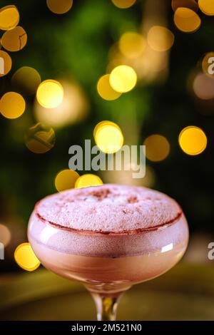 Cocktailgetränk mit Espresso-Kaffee in einem Coupé-Glas auf einem goldenen Tablett. Weihnachtsdekoration mit Lichtern im Hintergrund. Silvesterparty-Atmosphäre. Stockfoto