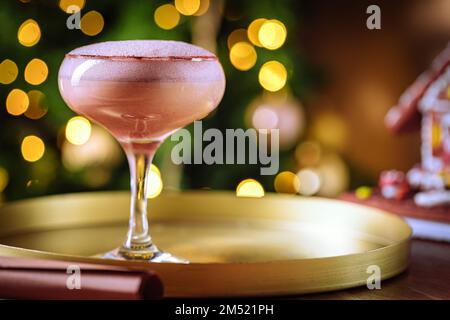 Cocktailgetränk mit Espresso-Kaffee in einem Coupé-Glas auf einem goldenen Tablett. Weihnachtsdekoration mit Lichtern im Hintergrund. Silvesterparty-Atmosphäre. Stockfoto