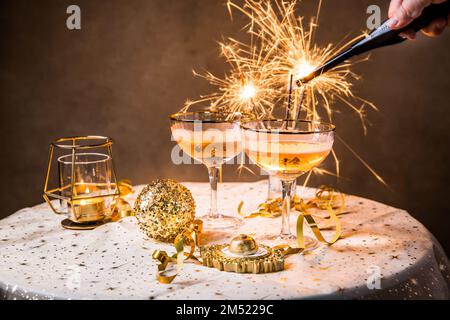 Zwei Gläser Sekt auf einem festlichen Tisch für Silvester, Party oder Karneval in goldenem und schwarzem Ton Stockfoto
