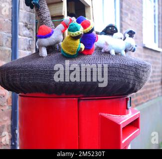 Postfach Royal Mail, oben mit kleinen gestrickten Weihnachtsfiguren weiser Männer dekoriert, in Upton auf Severn, Worcestershire, England. Die Geschichte ist, dass nach Jesus Geburt die Weisen nach ihm suchten. Konzept: Garnbombentrend. Stockfoto
